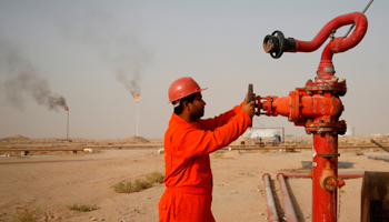 A worker adjusts the valve of an oil pipe at Najaf oil refinery in Iraq (Reuters/Ahmad Mousa)