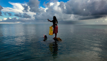 A woman stands on top of a rock in Kiribati (Reuters/David Gray)
