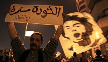 Activists and anti-government protesters hold a sign and wave a flag in Cairo (Reuters/Amr Abdallah Dalsh)