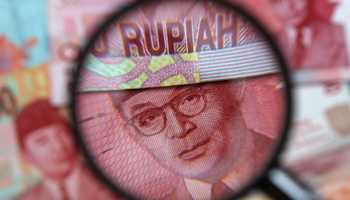 Rupiah notes are seen through a magnifying glass (Reuters/Edgar Su)