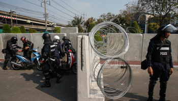 Riot police officers conduct a security check on motorcyclists near a barricade in Bangkok (Reuters/Athit Perawongmetha)