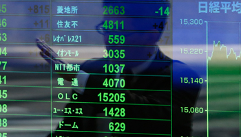 A pedestrian is reflected on a stock quotation board at a brokerage in Tokyo (Reuters/Yuya Shino)