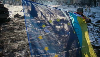 An anti-government protester places Ukrainian and EU flags on a barricade in Kiev (Reuters/Gleb Garanich)