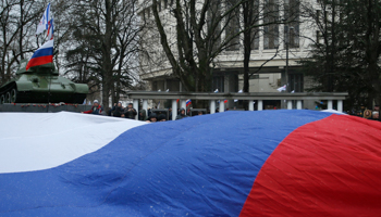 People hold a giant Russian flag during a pro-Russian rally near the Crimean parliament building in Simferopol (Reuters/David Mdzinarishvili)