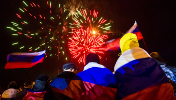 People wrapped with Russian flags watch fireworks in Simferopol (Reuters/Thomas Peter)