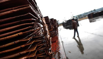 A man stands near copper cathodes south of Shanghai (Reuters/Carlos Barria)