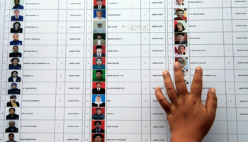 A woman places a hand on a list of candidates for members of parliament (Reuters/Beawiharta)