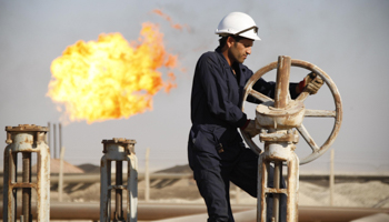 A worker adjusts the valve of an oil pipe at West Qurna oilfield (Reuters/Atef Hassan)