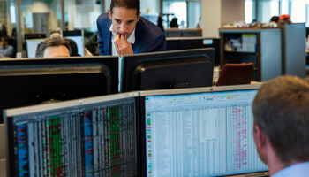 A Fund manager looks at the computer screens of a colleague (Reuters/Michael Kooren)