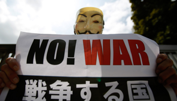 A protester holds a placard at a rally against Prime Minister Shinzo Abe's push to expand Japan's military (Reuters/Yuya Shino)