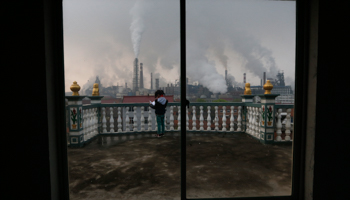 A girl reads a book on her balcony as smoke rises from chimneys of a steel plant, on a hazy day in Quzhou, Zhejiang province (Reuters/Stringer)