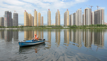 A man rows a boat on a river in front of new properties in Taiyuan, Shanxi province (Reuters/Stringer)