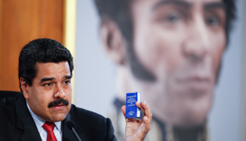 President Nicolas Maduro holds a copy of the country's constitution in front of a painting of South American revolutionary hero Simon Bolivar (Reuters/Miraflores Palace/Handout via Reuters)