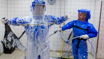 Ward physician Thomas Klotzkowski cleans doctor for tropical medicine, Florian Steiner, in a disinfection chamber at the Charite hospital in Berlin (Reuters/Thomas Peter)