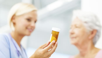 A doctor hands an elderly patient some medicines