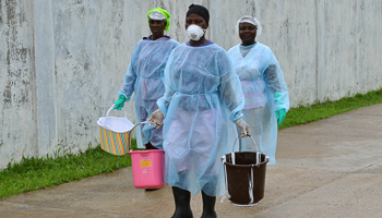 Health workers carry buckets of disinfectant at a treatment centre in Monrovia (Reuters/James Giahyue)