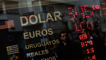 Pedestrians are reflected on the window of a money changer in Buenos Aires' financial district (Reuters/Marcos Brindicci)