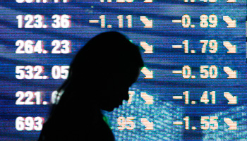 A woman walks in front of a stock quotation board in Tokyo (Reuters/Issei Kato)