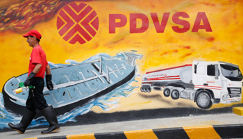 A worker walks past a mural with a PDVSA logo at a gas station in Caracas (Reuters/Carlos Garcia Rawlins)
