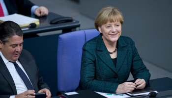 Chancellor Angela Merkel laughs next to Economy Minister Sigmar Gabriel after her speech during a debate at the lower house of parliament (Reuters/Stefanie Loos)