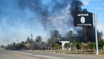 Smoke rises behind an ISG flag after Iraqi security forces took control of Saadiya in Diyala province (Reuters/Stringer)