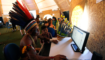 Brazilian indigenous people use computers inside a tent during the XII Games of the Indigenous People in Cuiaba (Reuters/Paulo Whitaker)