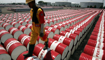 An employee of Indonesian oil company Pertamina walks on the top of drums at the oil storage depot in Jakarta (Reuters/Beawiharta)
