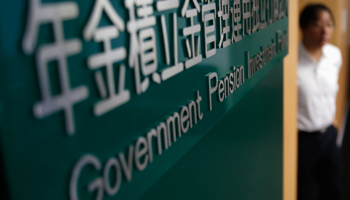 A man walks next to a signboard of Government Pension Investment Fund (Reuters/Yuya Shino)