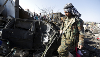 A Houthi fighter walks at the site of an air strike at a residential area near Sanaa Airport (Reuters/Khaled Abdullah)