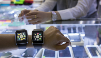 A salesman poses with two smartwatch devices, made by a Chinese manufacturer (Reuters/Tyrone Siu)