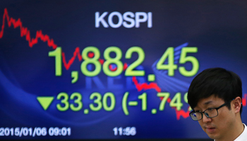 A currency dealer walks in front of an electronic board showing the Korea Composite Stock Price Index. (REUTERS/Kim Hong-Ji) 