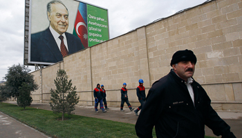 People walk in front of a billboard displaying a portrait of Heydar Aliyev in Baku (REUTERS/David Mdzinarishvili)