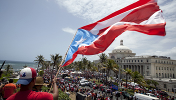 A man waves a national flag as protesters march through San Juan (Reuters/Alvin Baez)