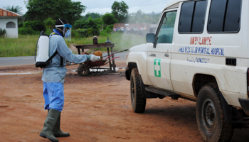 A health worker sprays disinfectant on an ambulance in Nedowein, Liberia (Reuters/James Giahyue)