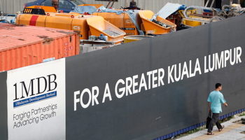 A man walks past a 1 Malaysia Development Berhad (1MDB) billboard in Kuala Lumpur (Reuters/Olivia Harris)