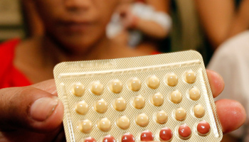 An NGO health worker holds contraceptive pills during a family planning session (Reuters/Erik De Castro)