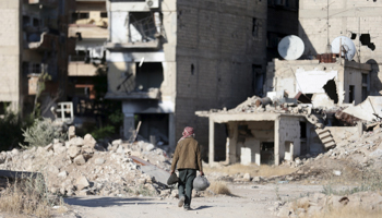 A man walks past damaged buildings along a street in Damascus, Syria (Reuters/Bassam Khabieh)