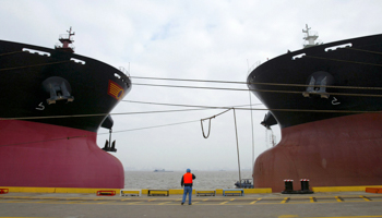 A worker stands in front of two Chinese Capesize bulk carriers (Reuters/Stringer)