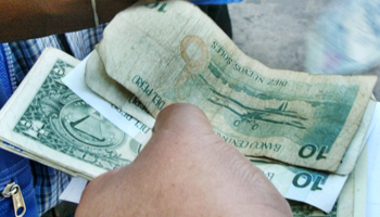 A Peruvian money changer counts notes on a street corner (Reuters/Pilar Olivares)
