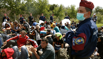 Hungarian policemen watch migrants near a collection point in Roszke, Hungary (Reuters/Marko Djurica)