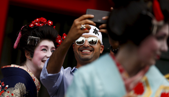 A man takes selfies with a tourist outside Sensoji temple in Tokyo (Reuters/Thomas Peter)