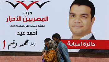 People in front of election poster for a parliamentary candidate of the Free Egyptians Party in the Warak district of Giza (Reuters/Mohamed Abd El Ghany)