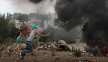 A Palestinian protester uses a sling to hurl stones towards Israeli troops during clashes near the Jewish settlement of Bet El, near the West Bank city of Ramallah (Reuters/Mohamad Torokman)