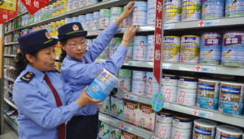 Chinese commercial law enforcement personnel inspect milk powder products at a supermarket in Lianyungang, Jiangsu province August 6, 2013 (Reuters/China Daily)