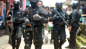 Armed anti-terror police walk ahead of guard officers carrying evidence from the house of a man suspected of being involved in Islamic State-related activities in south Tangerang (Reuters/Antara Foto/Muhammad Iqbal)