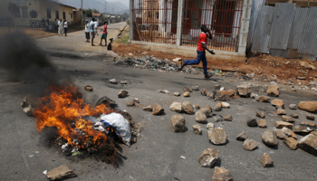 A man runs past a burning barricade, Burundi, July 21, 2015 (Reuters/Mike Hutchings)