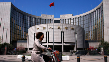 A woman rides past the headquarters of the People's Bank of China  (Reuters/Petar Kujundzic)