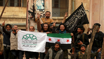 Rebel fighters pose carrying Ahrar Al-Sham, Free Syrian Army and Nusra front flags in Idlib city (Reuters/Ammar Abdallah)