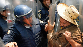 A demonstrator is pushed by riot police during a pension reform protest in Mexico City (Reuters/Daniel Aguilar)