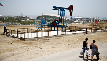 People walk past an oil pump in Baku (Reuters/Kai Pfaffenbach)